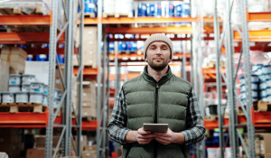 warehouse manager standing in a full warehouse with an e-tablet